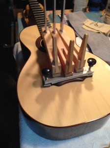 Bridge being attached with hide glue on parlor guitar by © Jay Rosenblatt