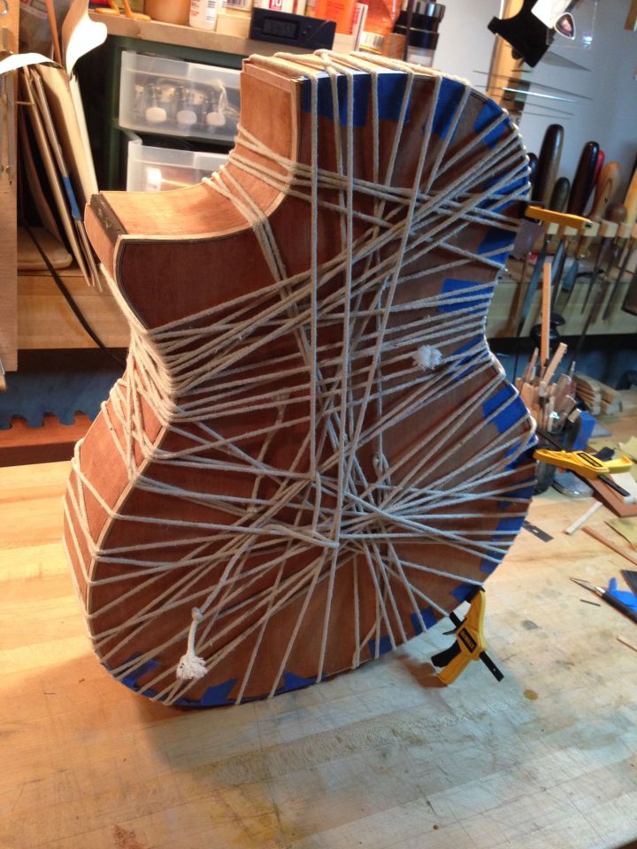 Roping curly maple binding in place on a Mahogany venetian cutaway acoustic guitar